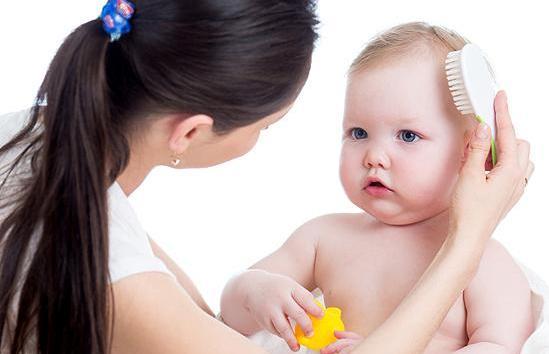 mother is combing baby`s hair after bathing